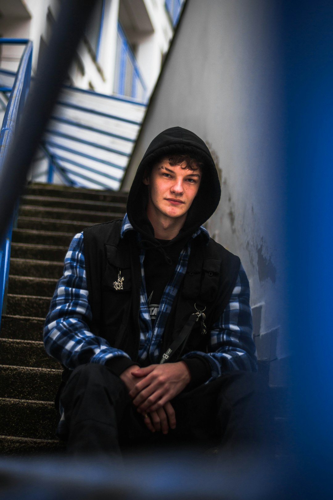 man in black and blue plaid jacket sitting on stairs