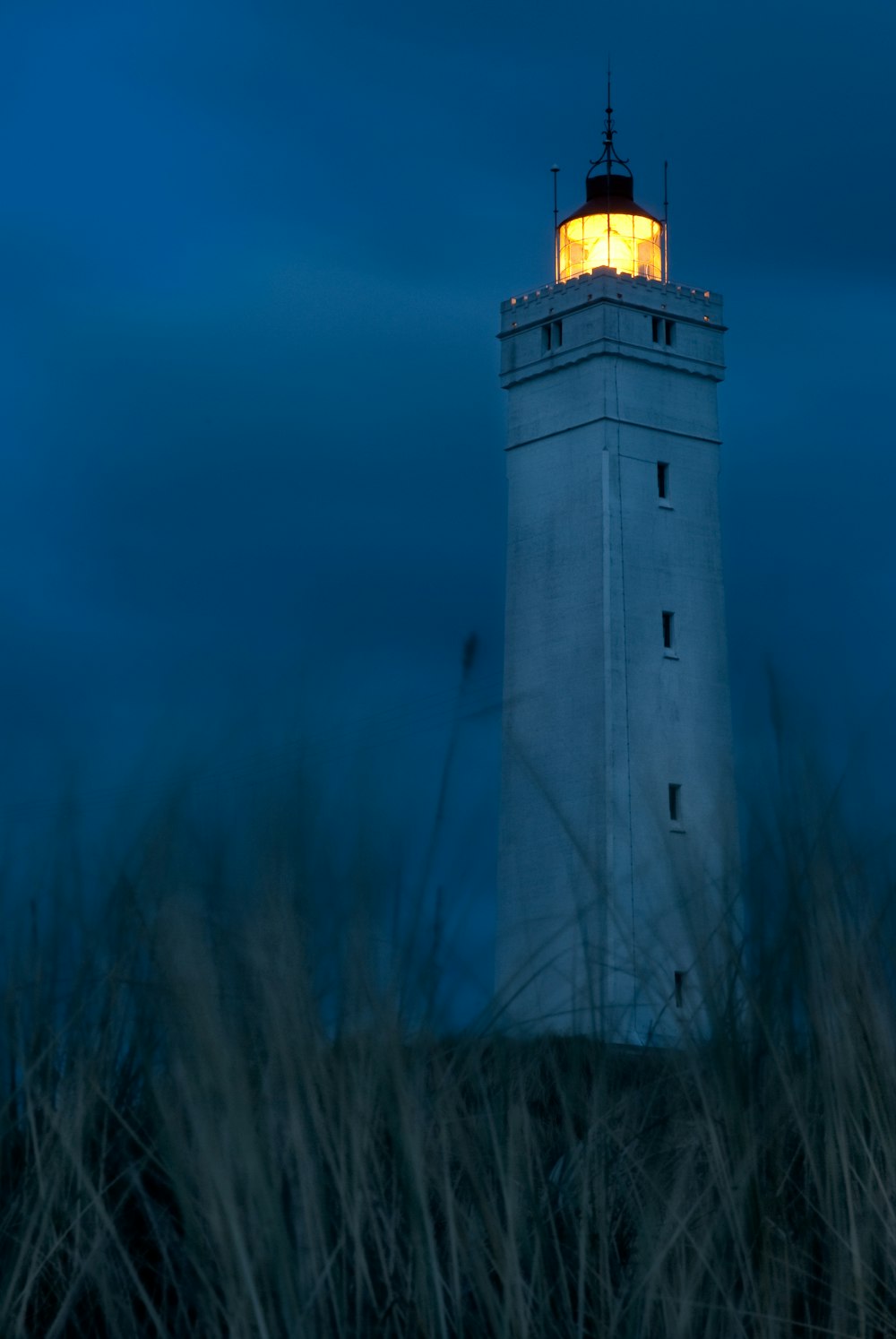 a white lighthouse with a yellow light on top of it
