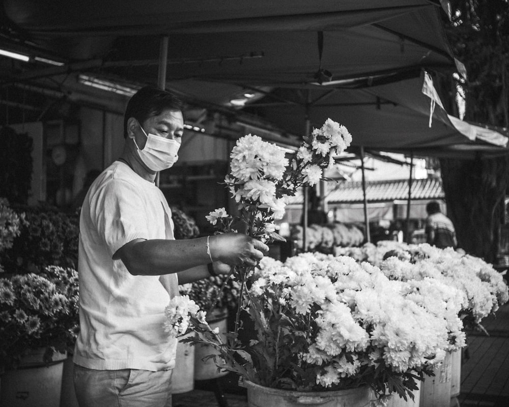grayscale photo of man in white shirt holding bouquet of flowers
