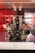 A high-performance engine is displayed on a platform, showcasing its complex mechanical components. The engine appears to be a V12 configuration with a mix of metal parts, belts, and pulleys. The backdrop features a red and black pattern, contributing to a modern and technical ambiance.
