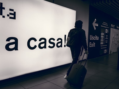 A friendly driver greeting a passenger with a suitcase at Milan Malpensa airport.