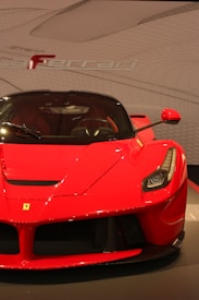 A sleek and shiny red sports car with distinctive features and a prominent emblem on the hood. The background showcases an abstract design with the brand name subtly displayed.