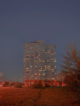 Finished residential building illuminated with yellow lights at dusk, showcasing quality construction.