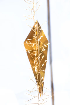 Close-up of a sleek, modern sound sculpture with delicate wires and glowing nodes against a dark background.