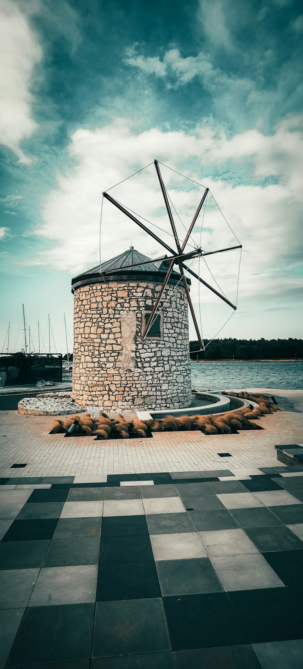 Braune und schwarze Windmühle in der Nähe von Gewässern tagsüber