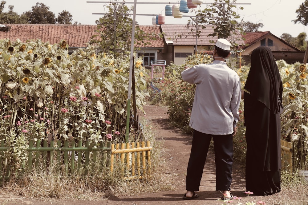 man in white dress shirt and black pants standing near green plants during daytime