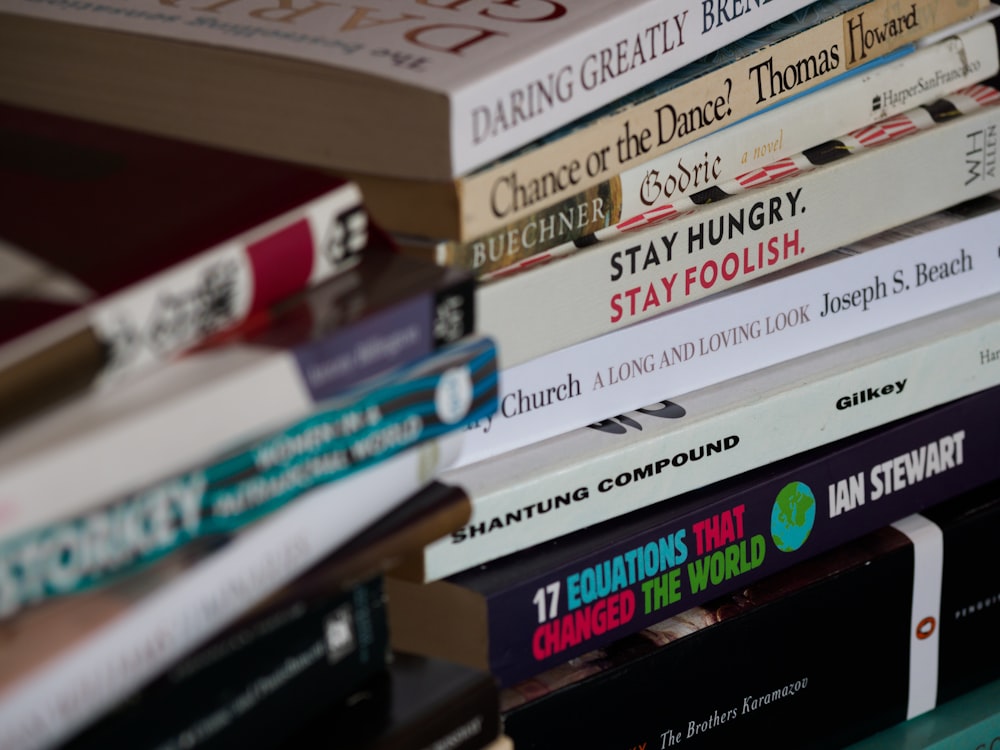 assorted books on brown wooden shelf