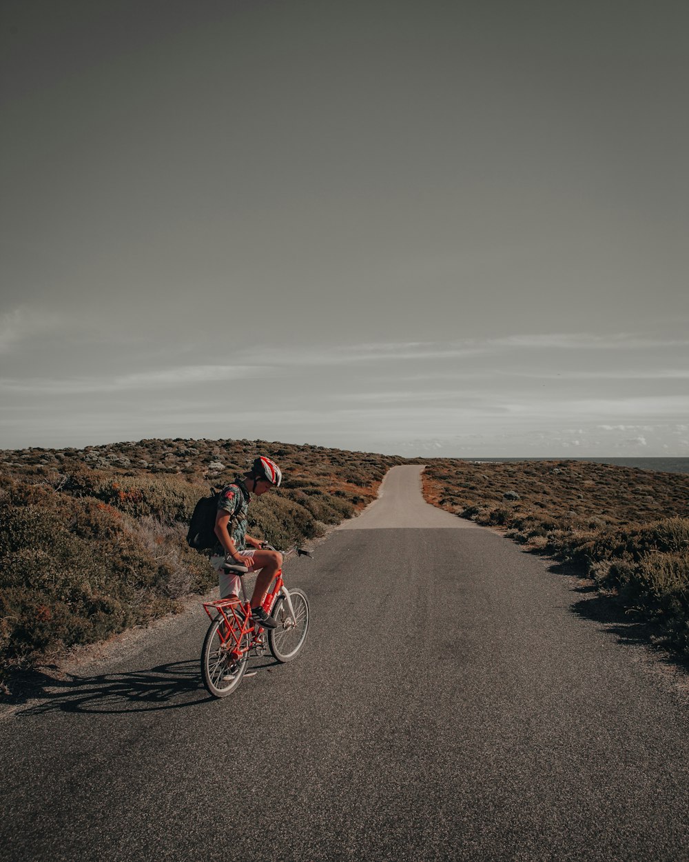 man in red shirt riding on bicycle on brown dirt road during daytime