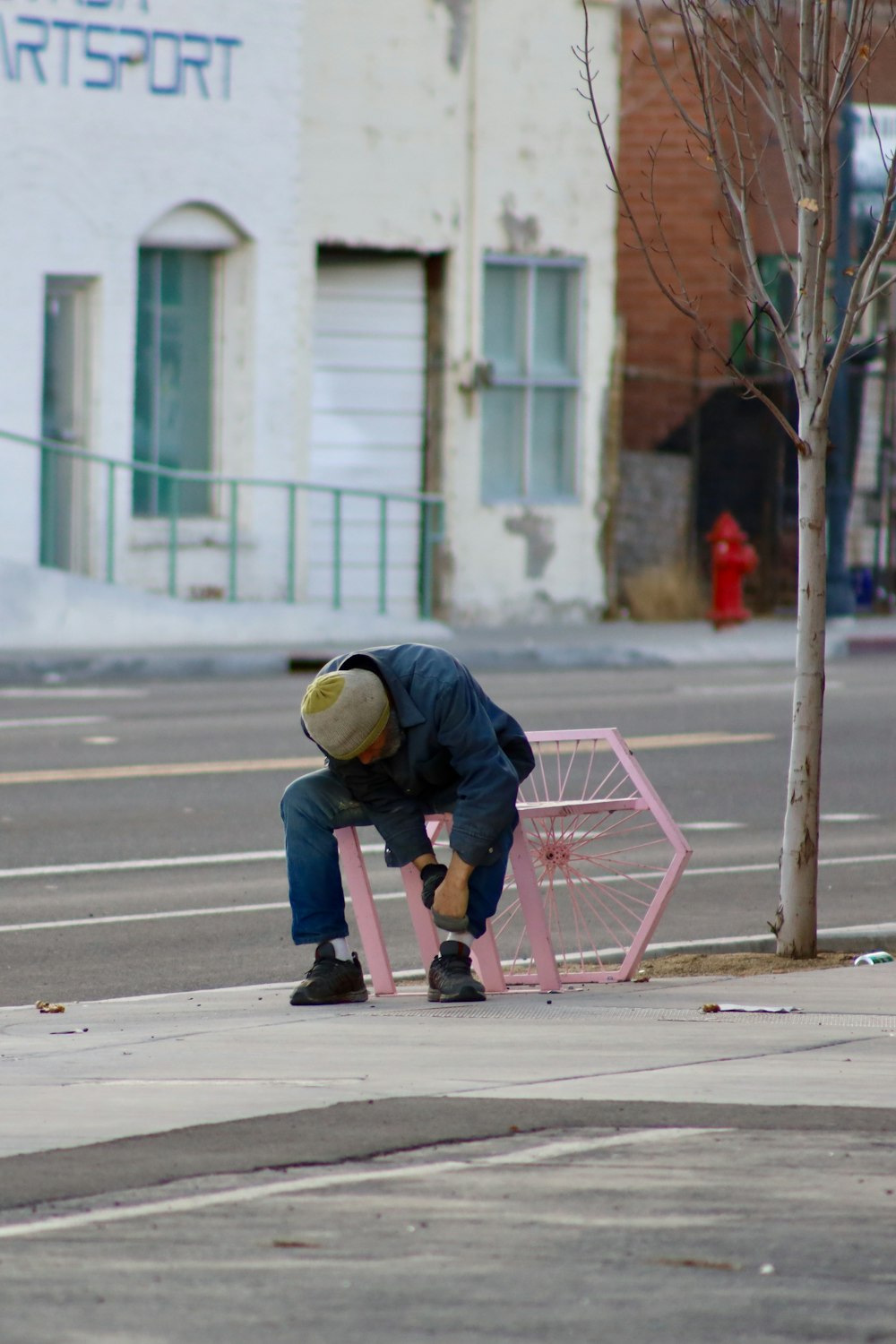 person in black jacket and yellow helmet riding pink kick scooter on sidewalk during daytime