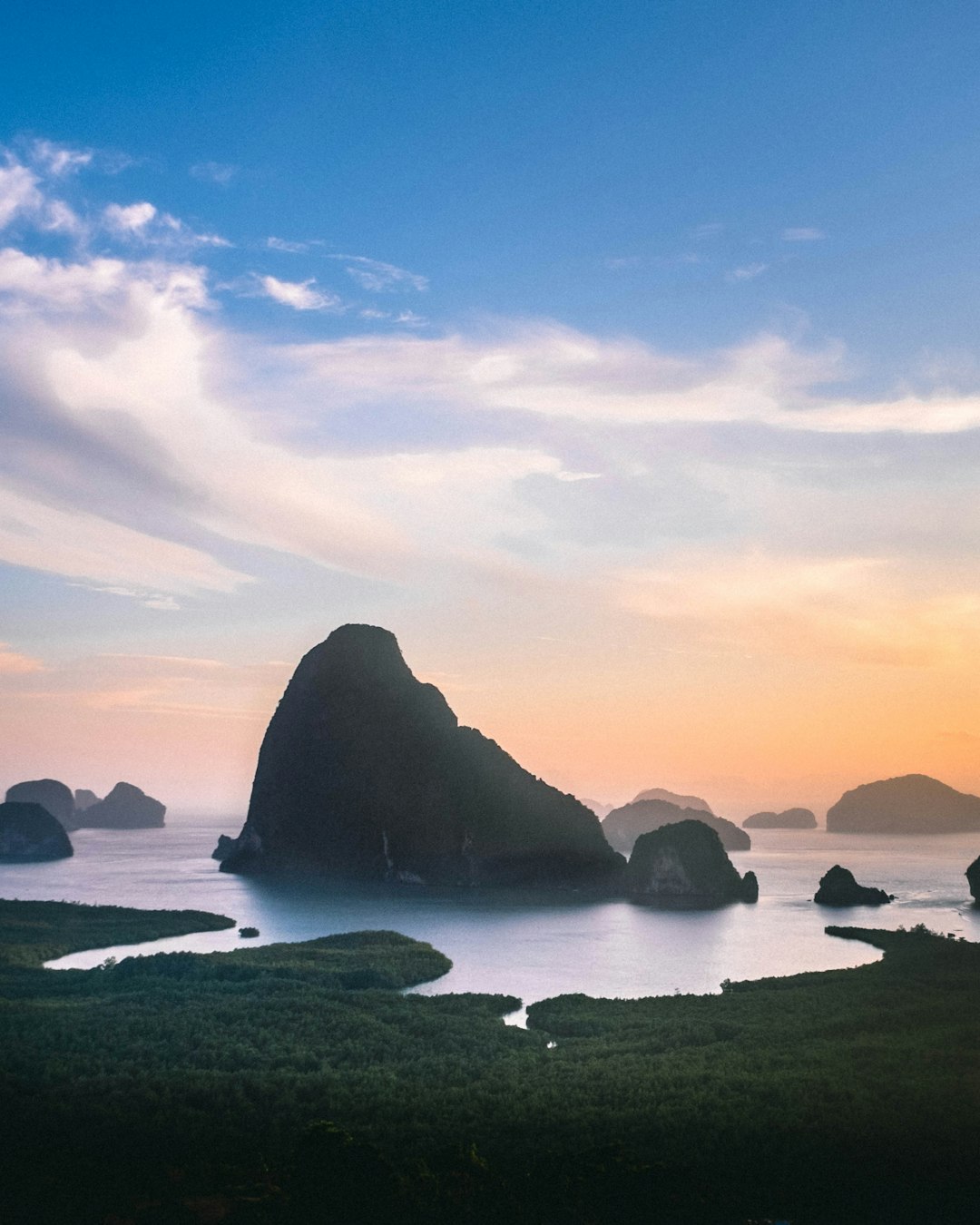 silhouette of rock formation on sea during sunset