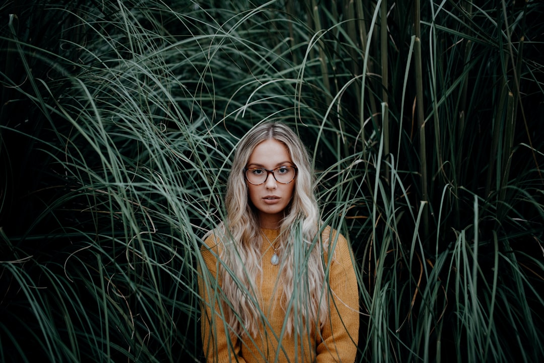 woman in brown coat standing on green grass field during daytime