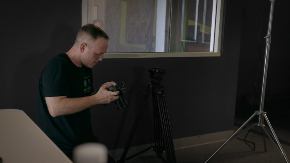 man in black crew neck t-shirt holding black camera