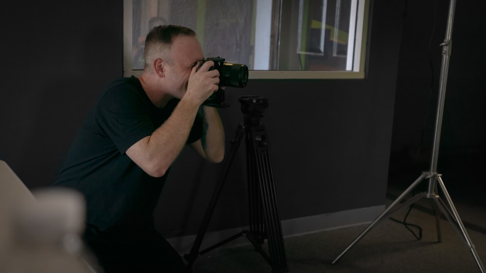 homme en noir ras du cou t-shirt utilisant un appareil photo reflex numérique noir