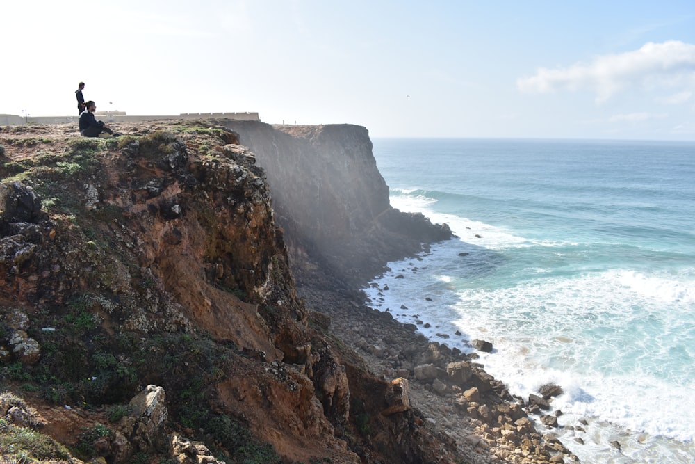 brown rocky mountain beside sea during daytime