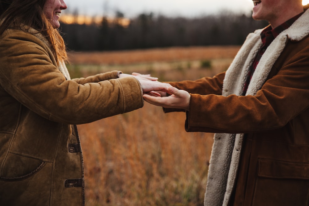 woman in brown coat holding mans hand