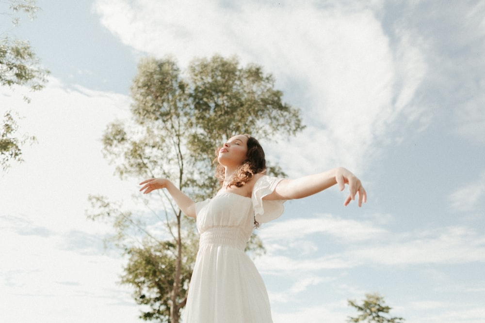 woman in white dress standing and raising her hands