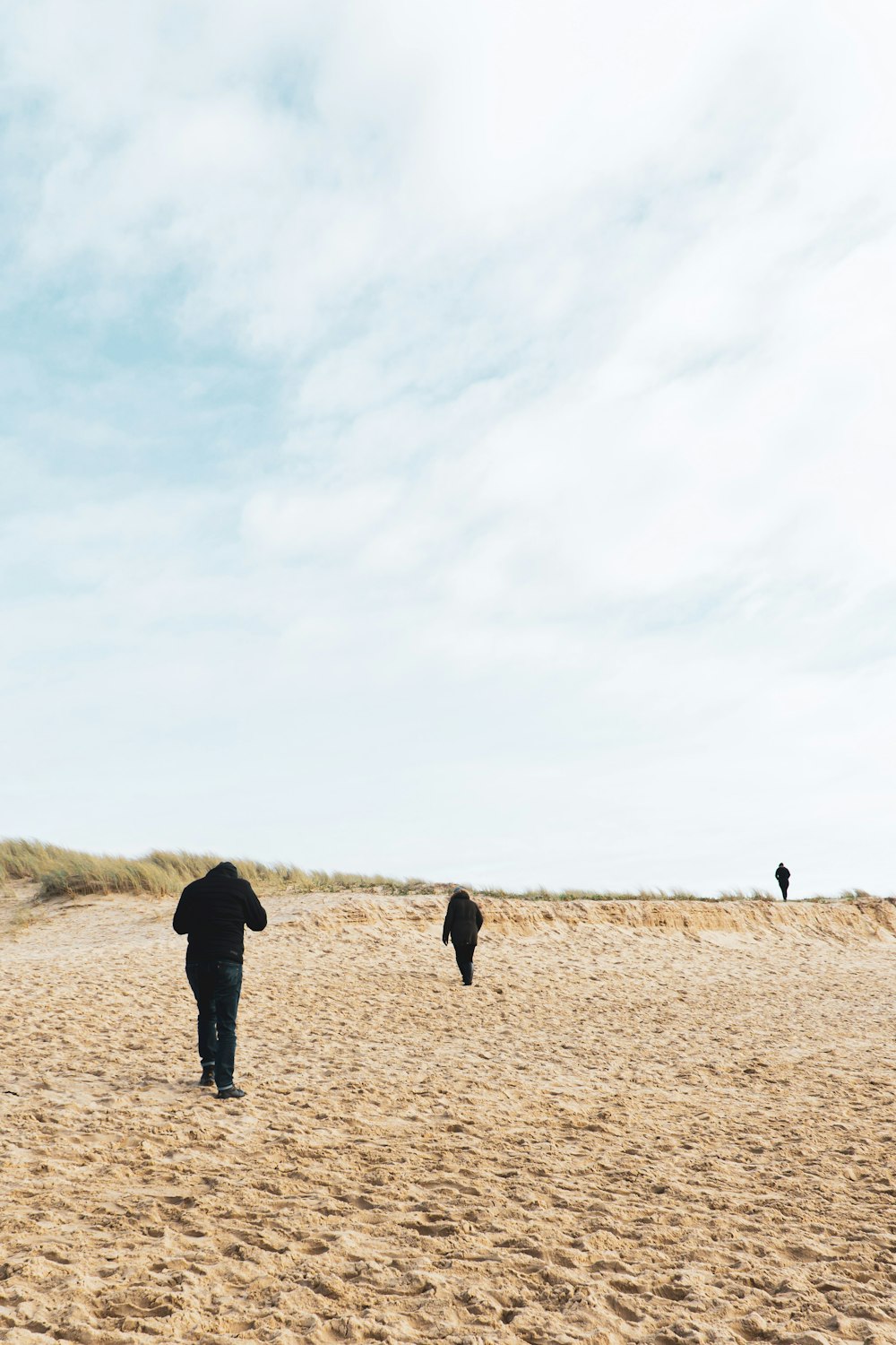 people walking on brown field under white clouds during daytime