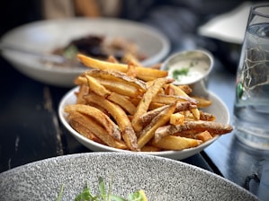 A plate of crispy golden fries served with dipping sauces.
