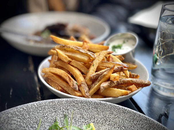 A colorful platter featuring crispy golden fries alongside a tangy dipping sauce
