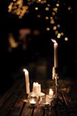 Several handmade candles arranged on a rustic wooden table, their flames reflecting warmth.