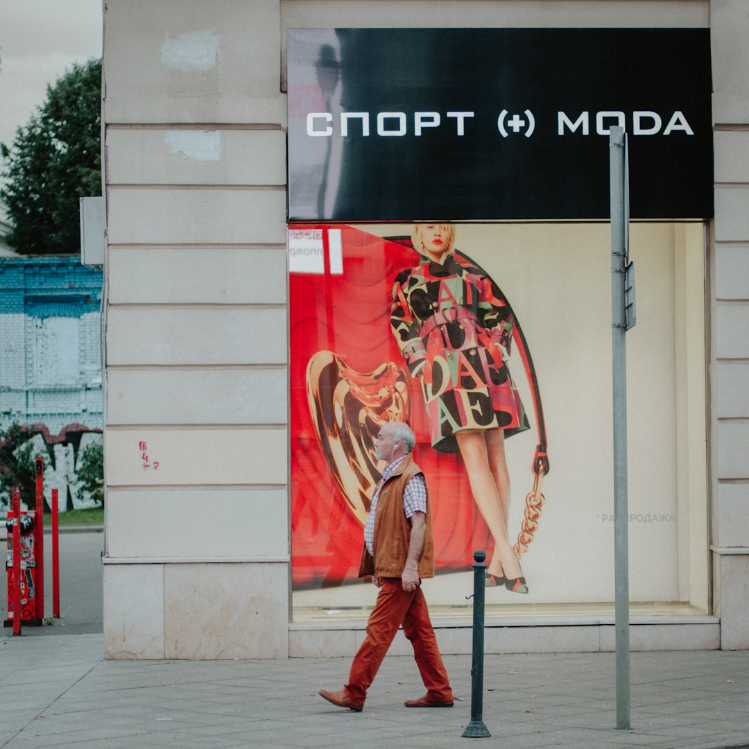 man in red and gold coat standing near red and white concrete building during daytime