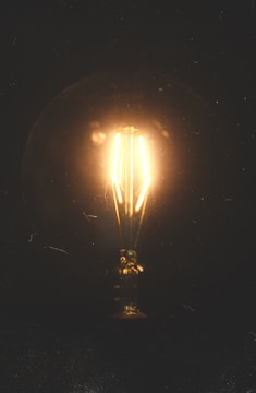 A glowing lightbulb bursting with colorful sparks against a dark background.