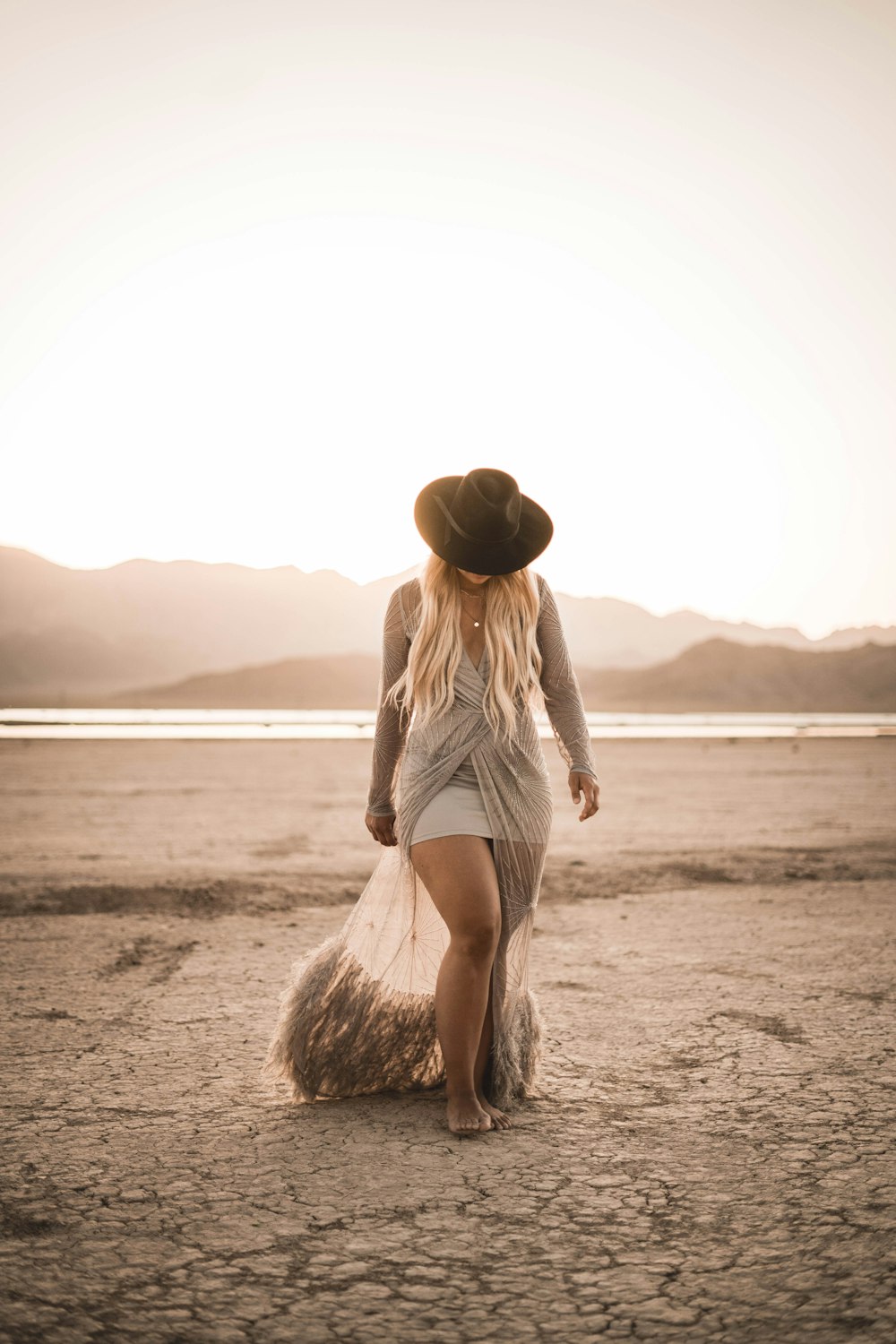 Mujer con camiseta blanca sin mangas y pantalones cortos blancos caminando en la playa durante el día