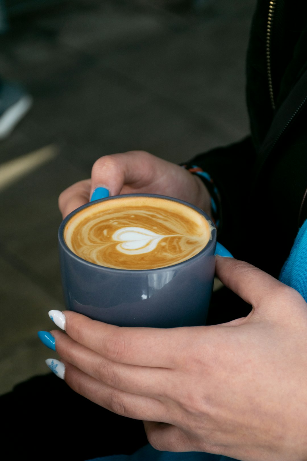 person holding blue ceramic mug with brown liquid