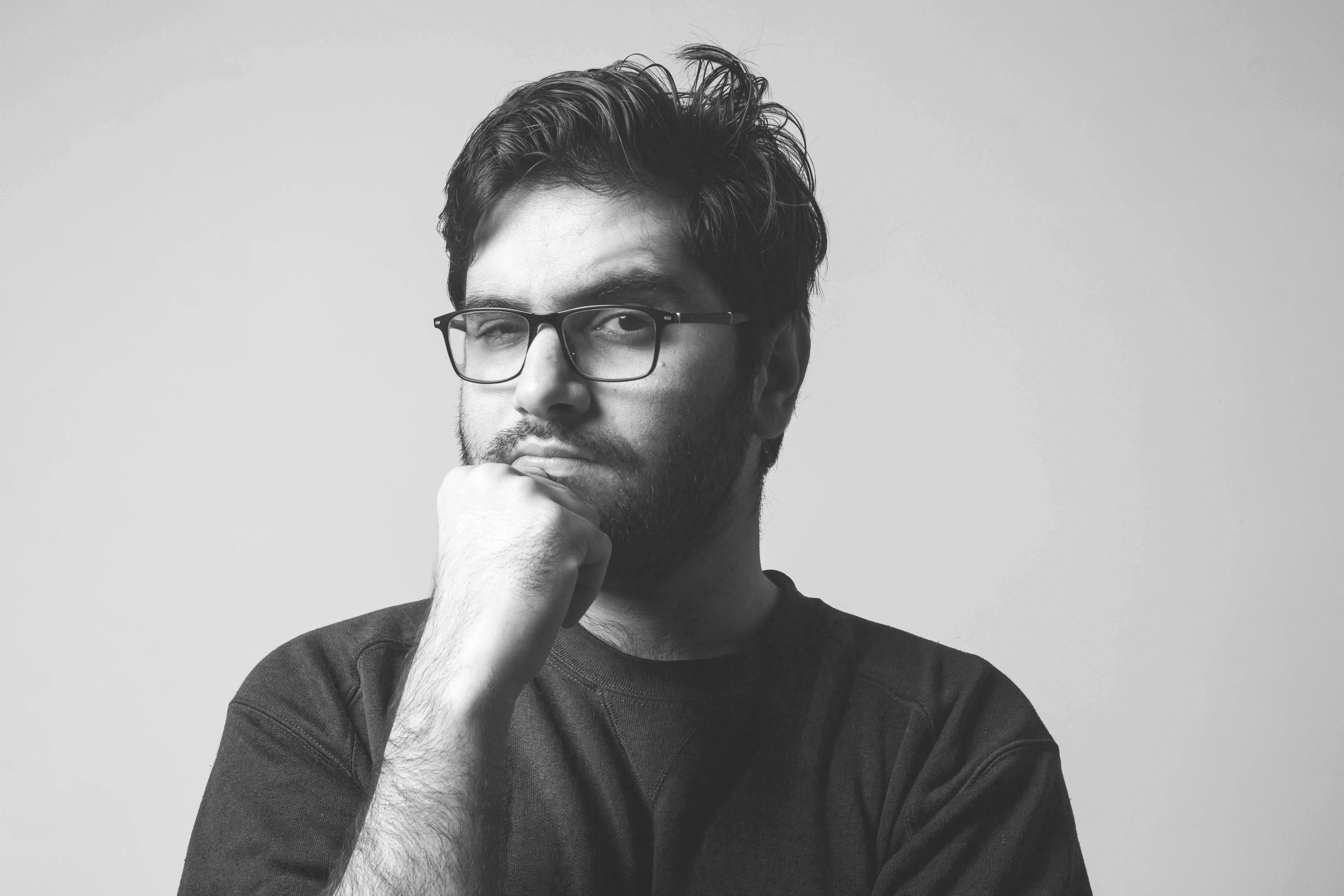Black and white mid body shot of a man thinking and staring in a room