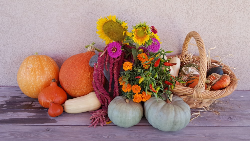 yellow sunflower and orange pumpkins on white wooden table