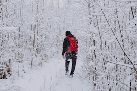 man in black jacket walking on snow covered ground during daytime