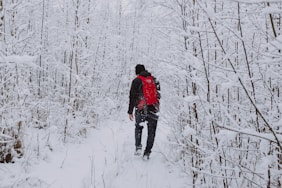 man in black jacket walking on snow covered ground during daytime