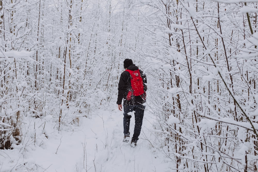 man in black jacket walking on snow covered ground during daytime