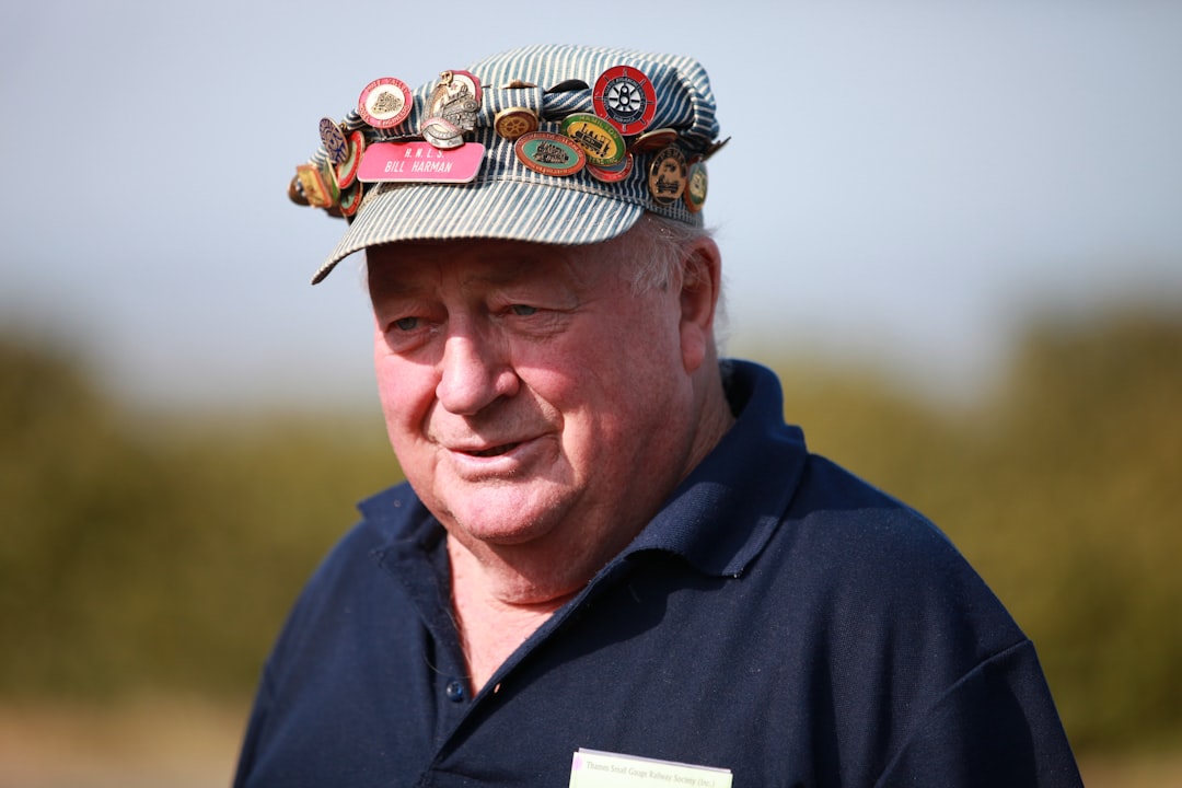 man in black polo shirt wearing green and red hat