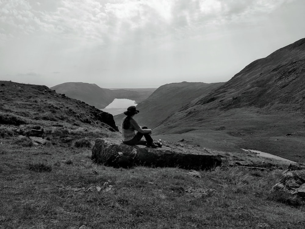 man sitting on rock near mountain during daytime