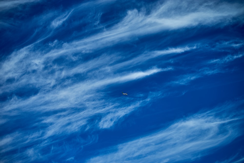 airplane in mid air under blue sky and white clouds during daytime