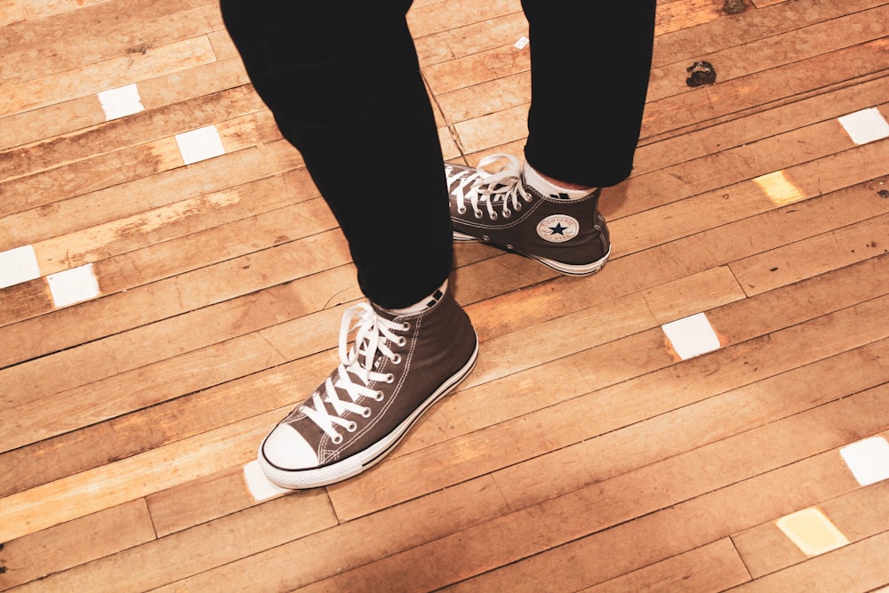 person wearing black pants and black and white converse all star high top sneakers