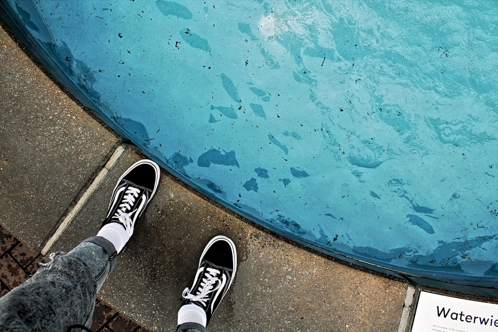 person wearing black and white sneakers standing on blue and brown concrete floor