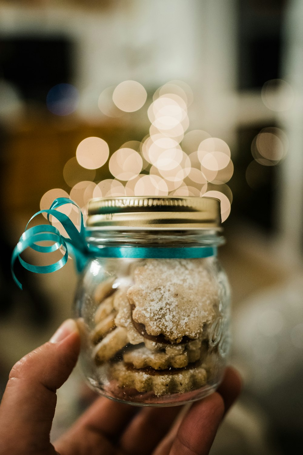 person holding clear glass jar with brown powder