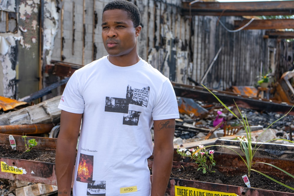 man in white crew neck t-shirt standing near green leaves during daytime