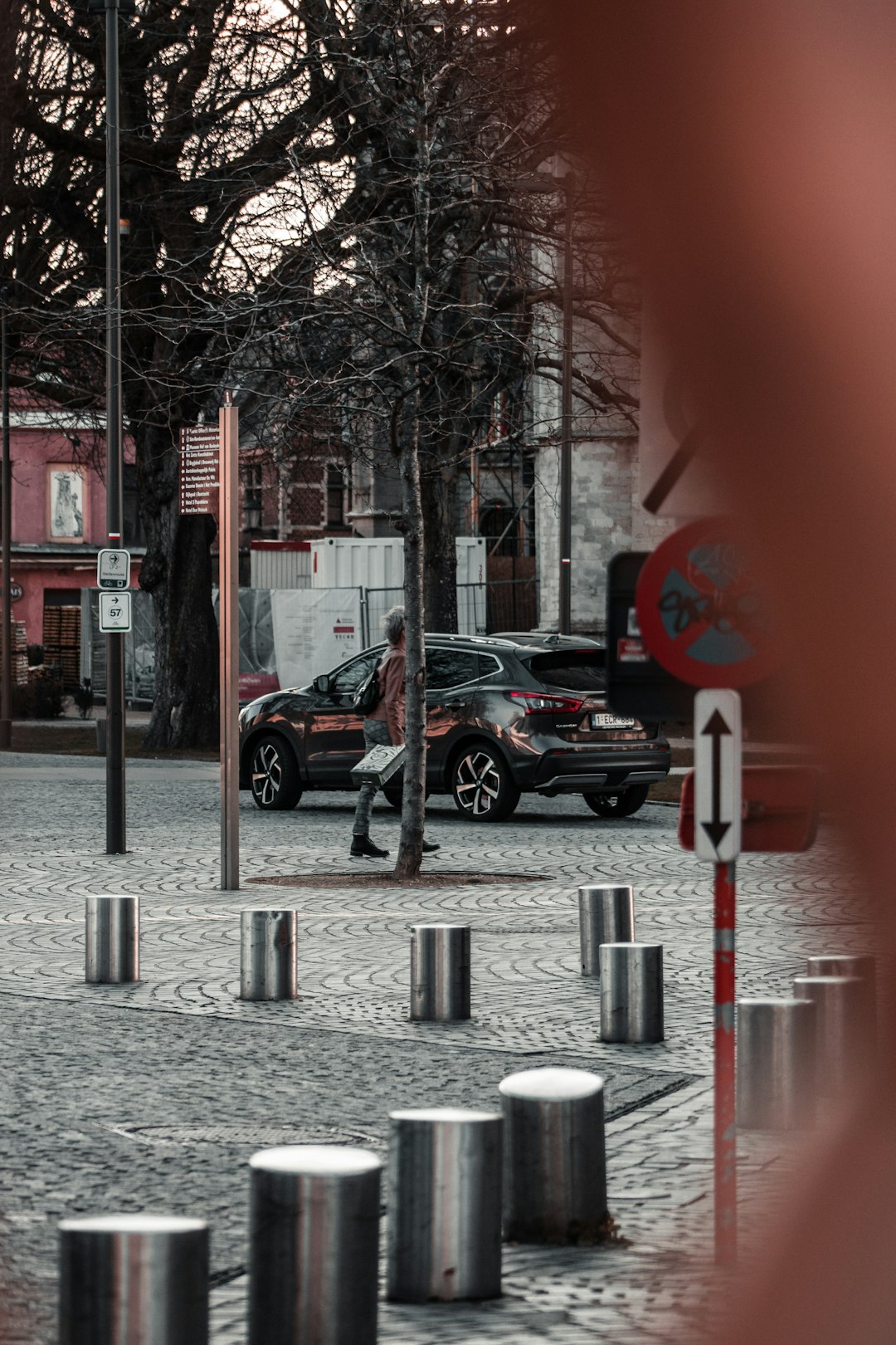 black sedan parked beside bare trees during daytime