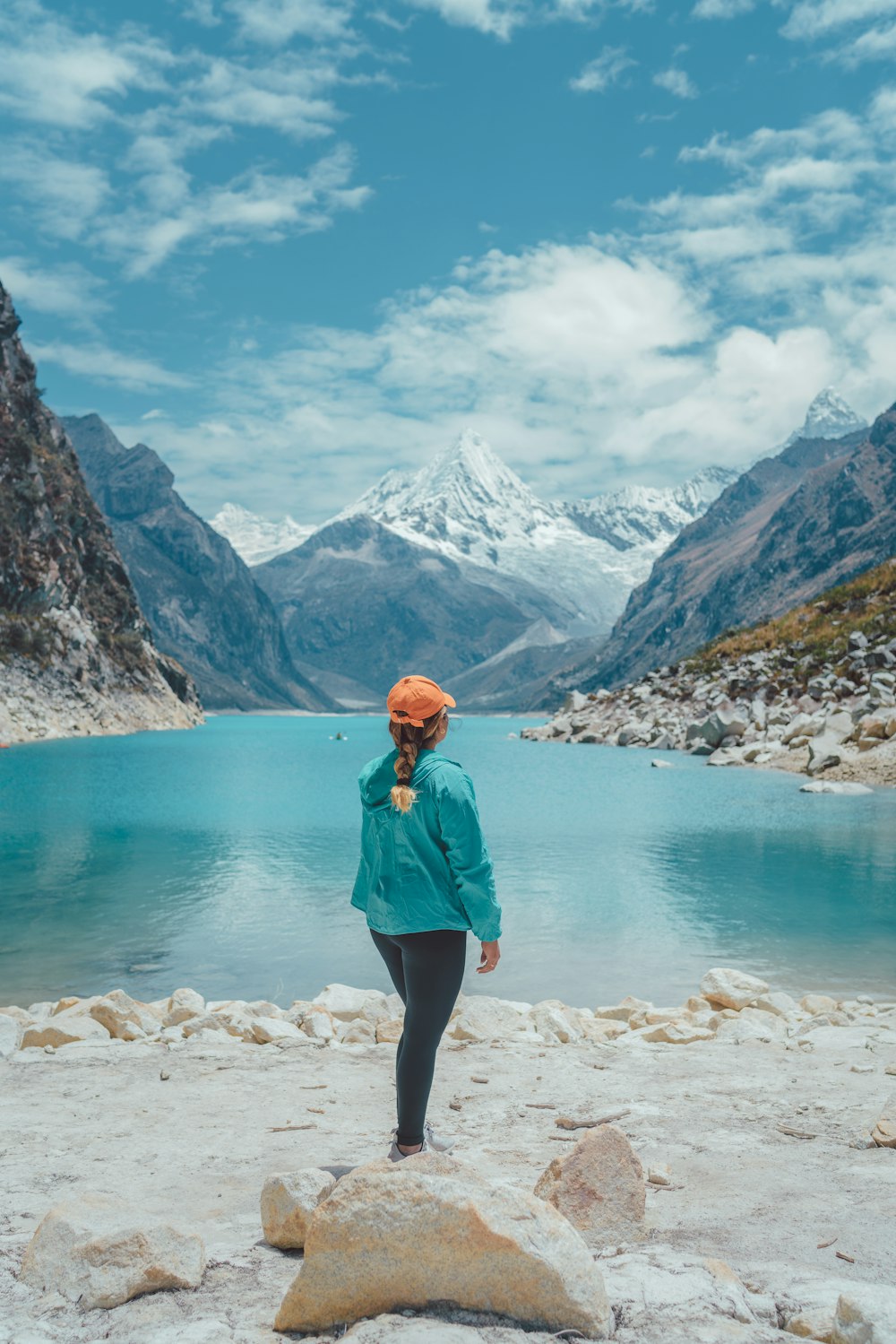 woman in blue jacket standing on white rocky shore during daytime