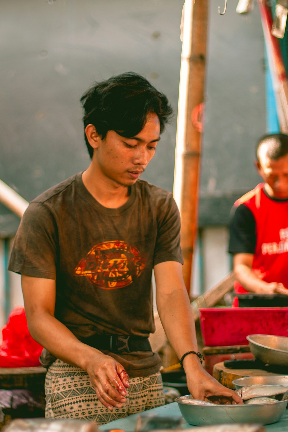 man in brown crew neck t-shirt standing beside red plastic container