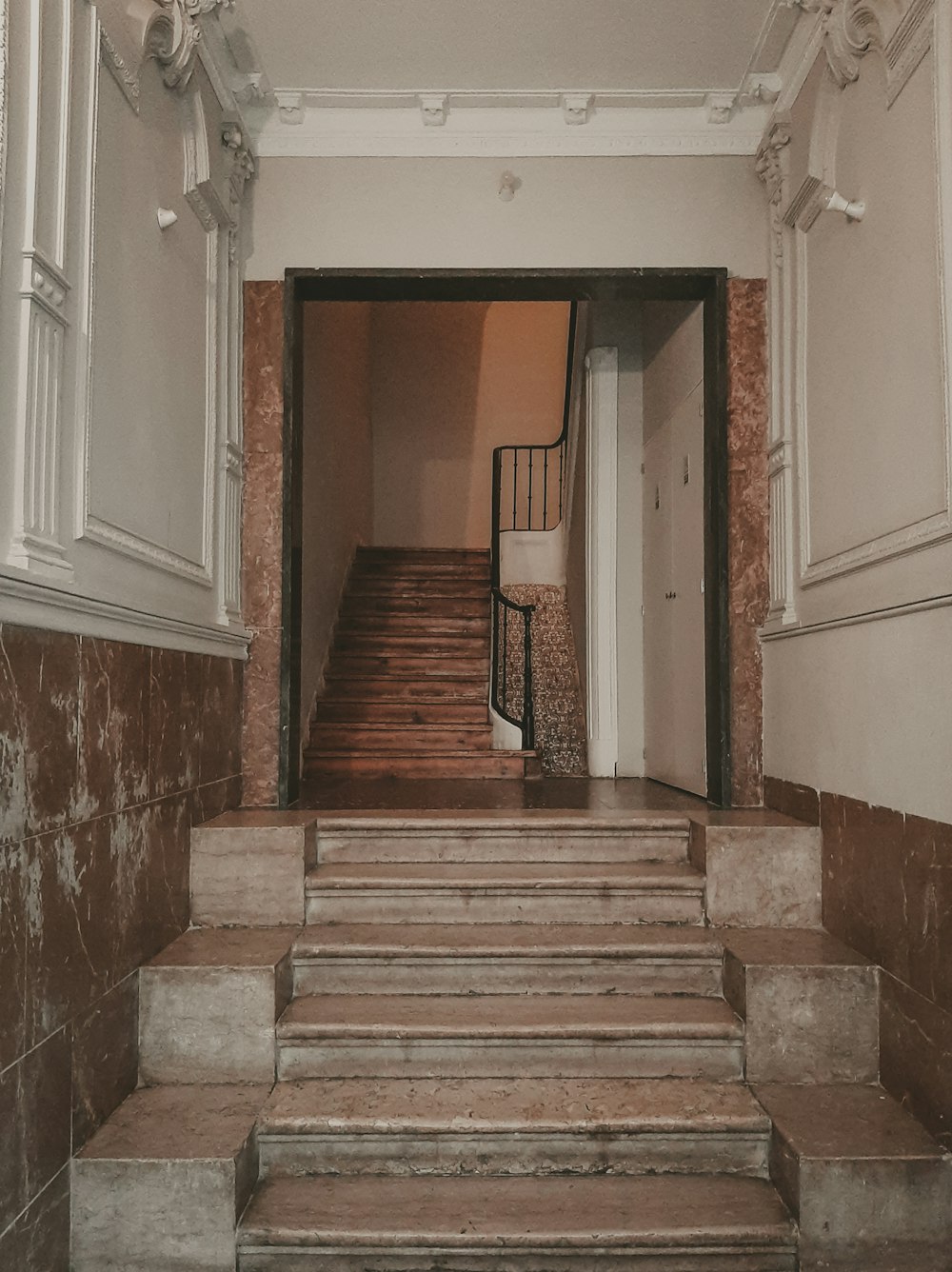 Escalera de madera marrón frente a la puerta de madera blanca