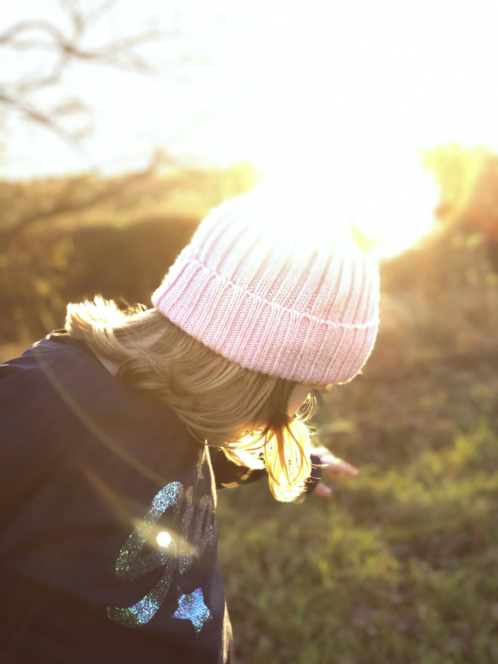 woman in pink knit cap and black jacket looking at the sun