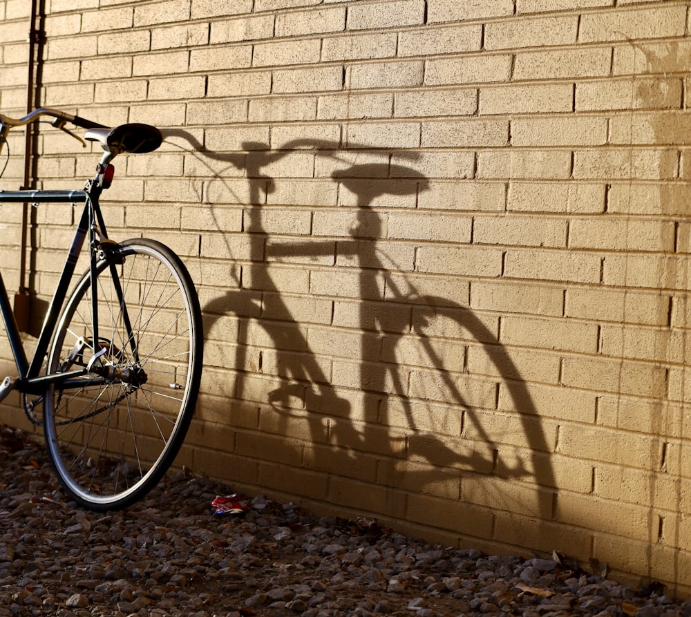 black bicycle leaning on wall