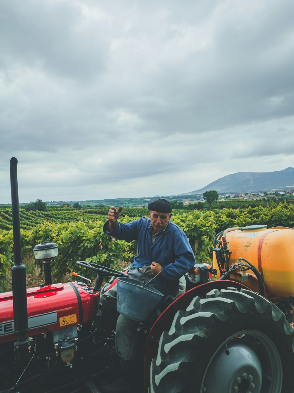 man in blue dress shirt riding red tractor during daytime