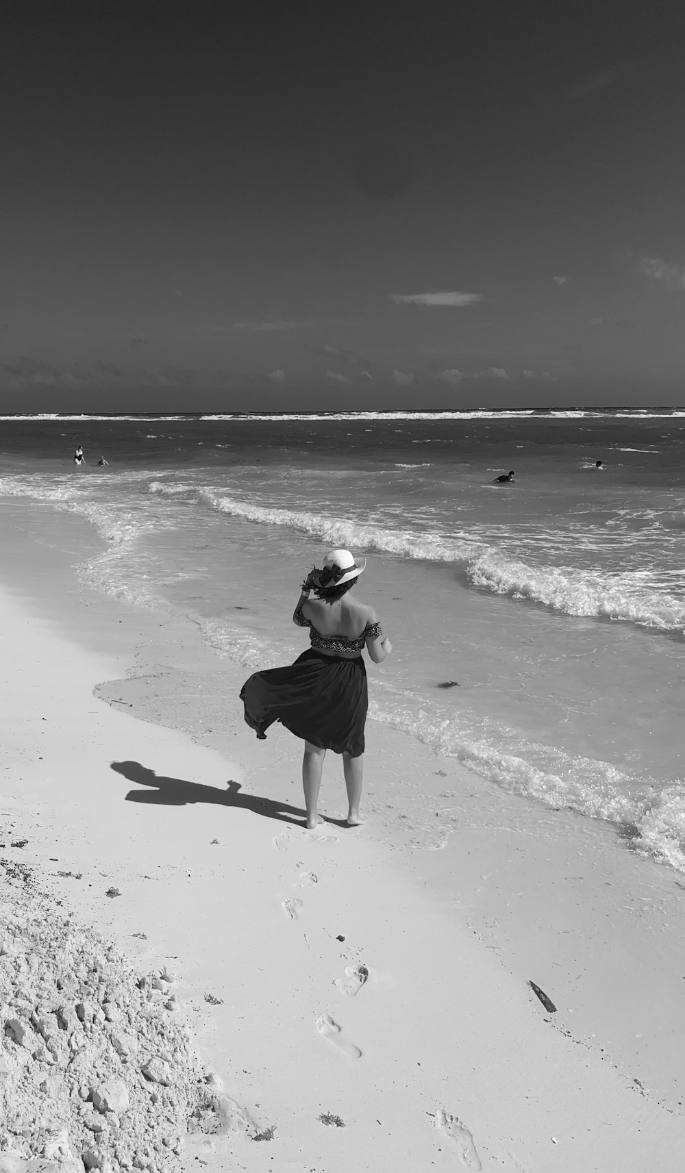 woman in black tank top and black pants walking on beach shore