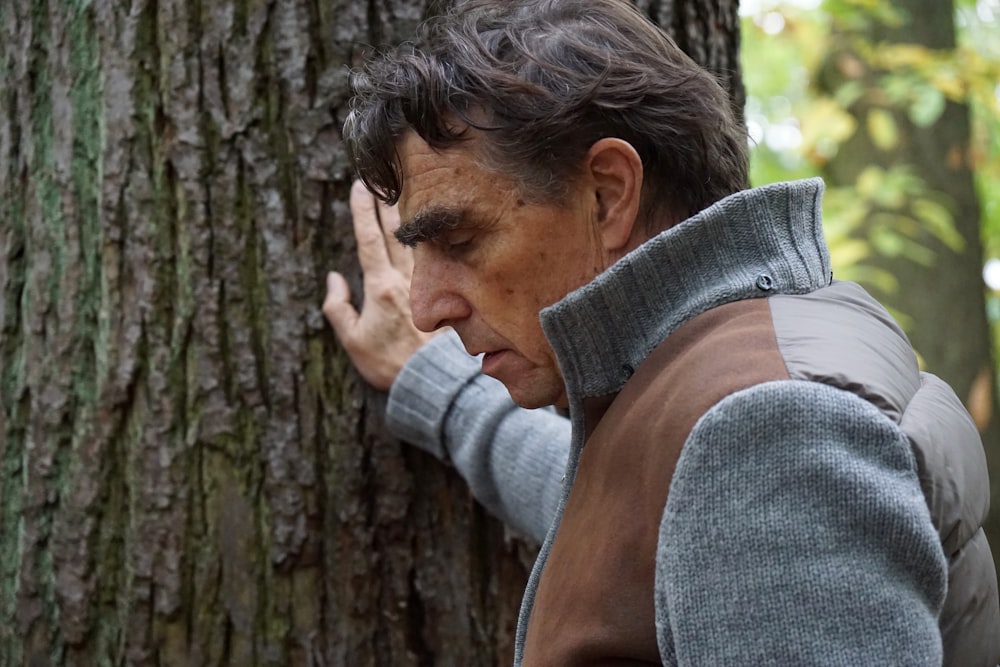 man in gray sweater covering face with his hand