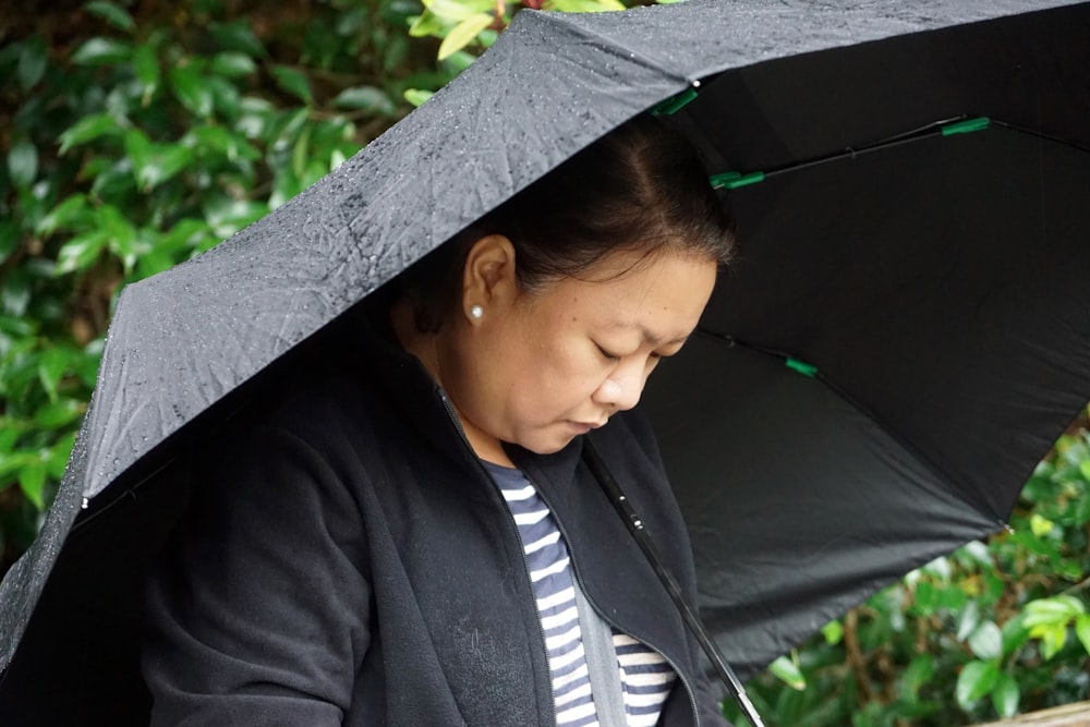 woman in black blazer and white and black striped shirt under black umbrella